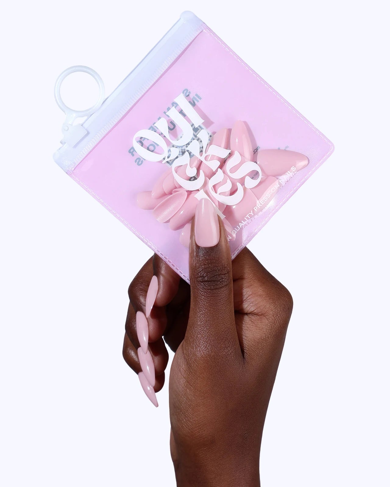 Hand holding a Quickies pouch, wearing pink stiletto press-ons