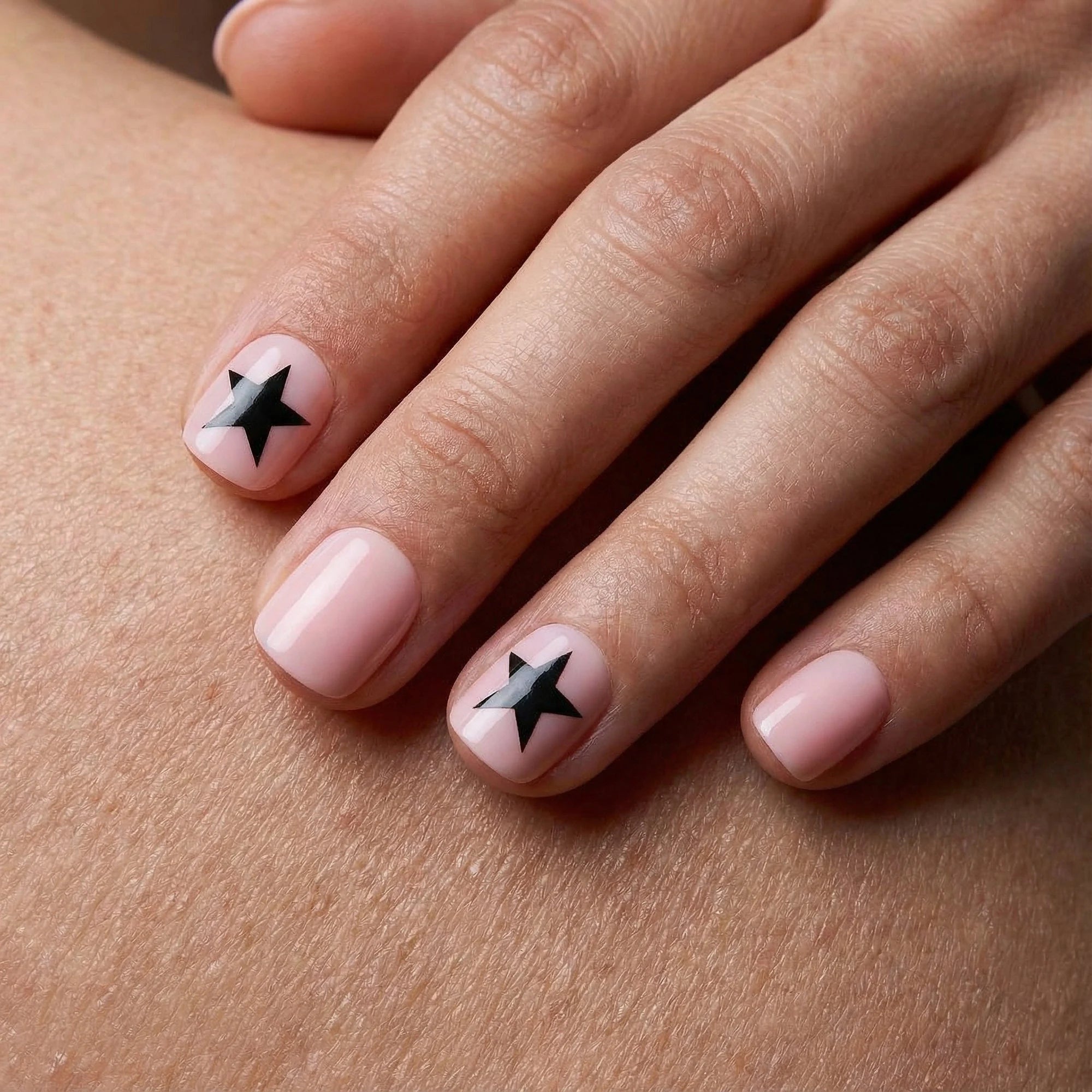 Short pink press-on nails with black star accents